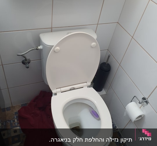 אסלה עם מים עומדים ומגבת רטובה על הרצפה
